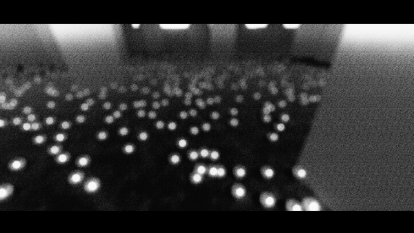 Screenshot from city::ephemera with the camera view open all the way, looking down at a lot of orbs scattered on the ground and large abstract buildings in the background. The image is grainy and black-and-white.