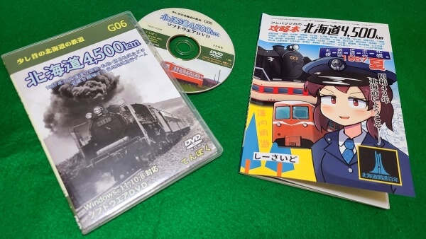 DVD case and disc of Hokkaido 4,500 next to the accompanying booklet, which looks like a train time table book with an anime stationmaster on the cover